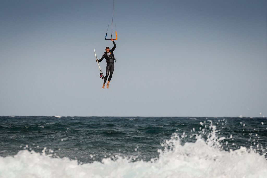 a kiteboarder suspended in the air holding the board during a freestyle trick